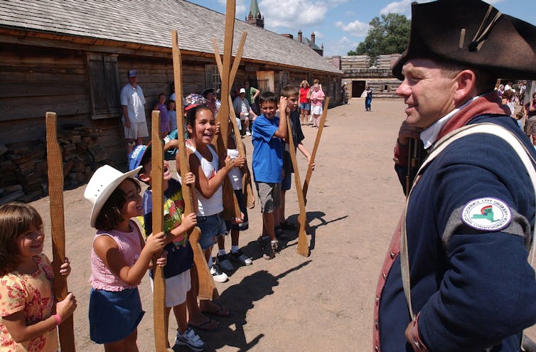 Kids and a worker in a soldier's uniform at Fort Stanwix, a reconstructed fort in the shape of star.