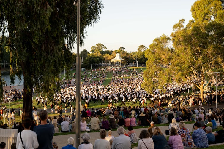 A crowd of people watches a crowd of dancers.