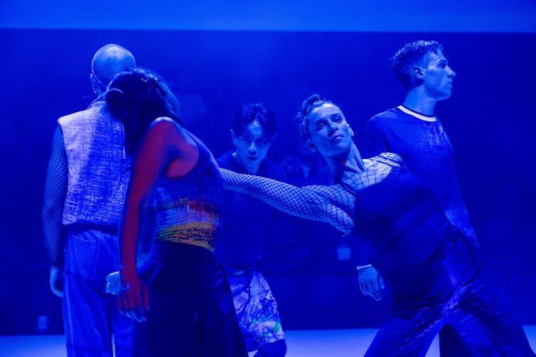 People dance under a blue light.