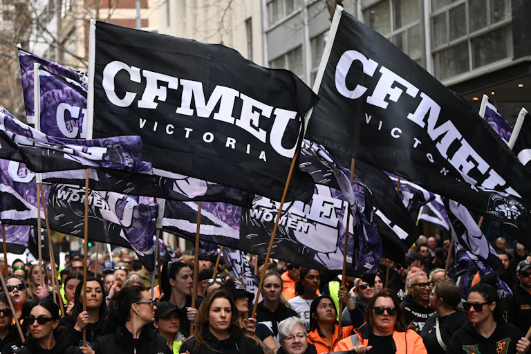 Doezens of men and women marching down a street waving union banners