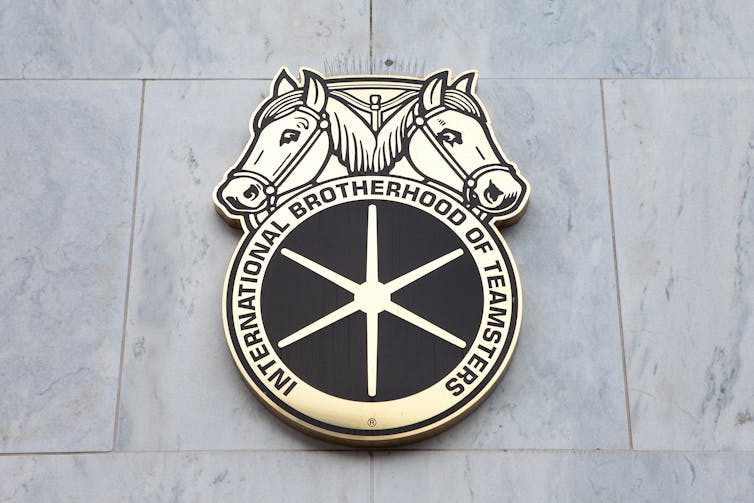 A Teamsters union emblem with two horse heads attached to a grey wall.