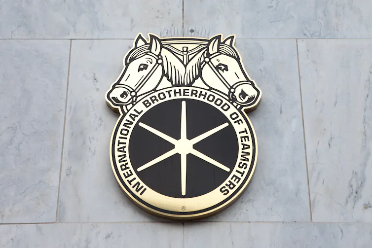 A Teamsters union emblem with two horse heads attached to a grey wall.