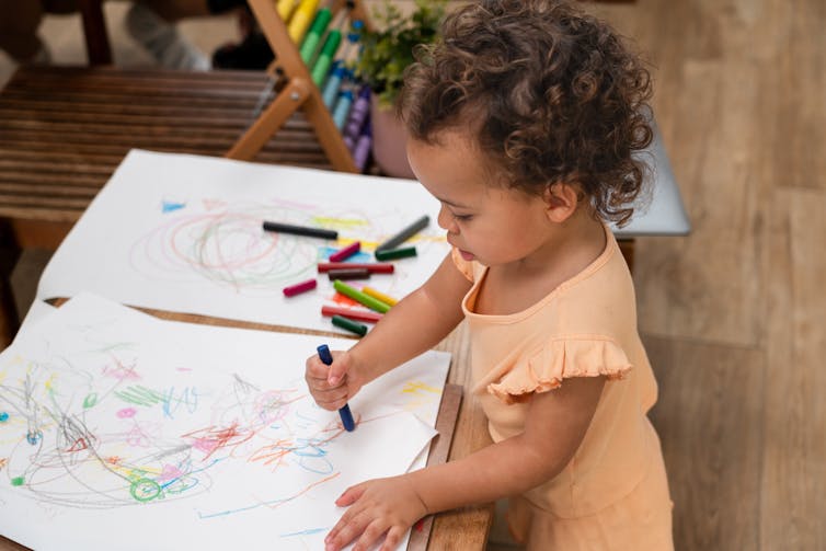 A young child draws with crayons.