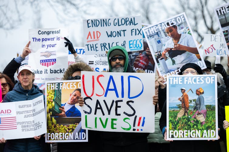 Protesters hold signs in support of USAID.