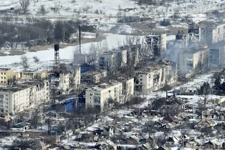 Aerial shot of a destroyed city with smoke billowing from some highrise apartment windows