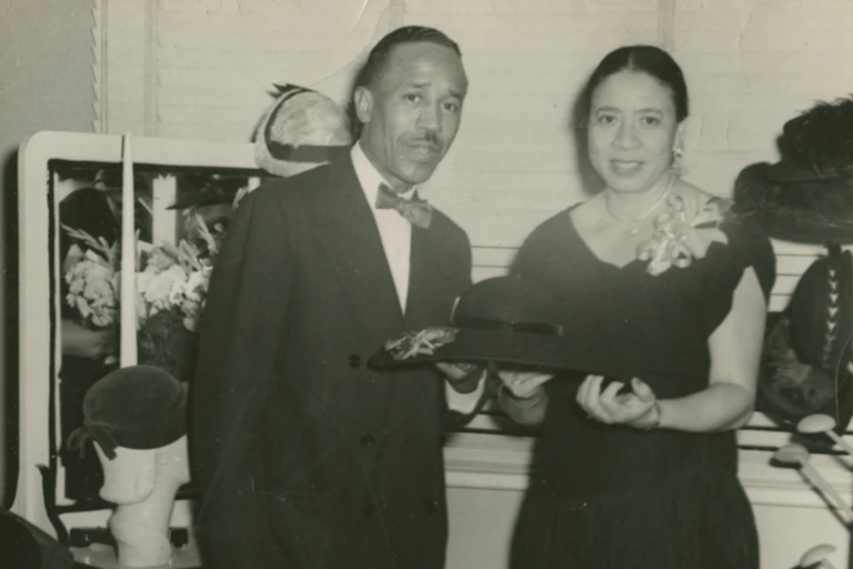 Black-and-white photo of well-dressed couples holding a formal black ladies hat