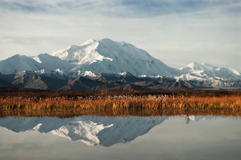 A view of a mountain across a still lake, with a reflection in the water.