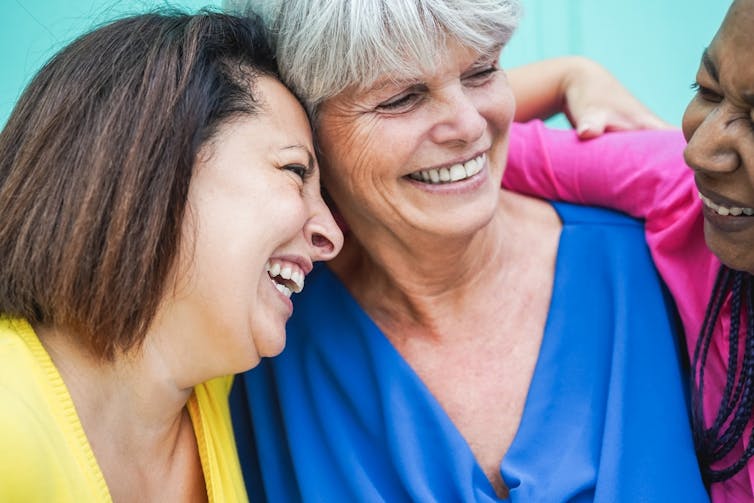 Three middle-aged women laughing.