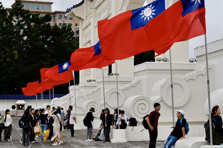 Young people gather around a biulding in Taipei where there are many Taiwanese flags flying.