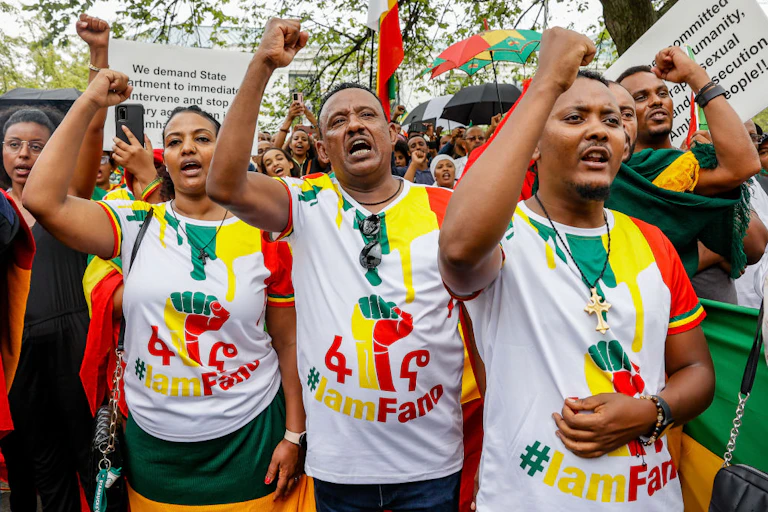 A group of people holding up their arms in tight fists, wearing T-shirts that say 'I am Fano'