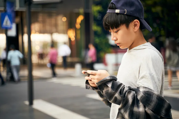 Un jeune garçon regarde son téléphone portable