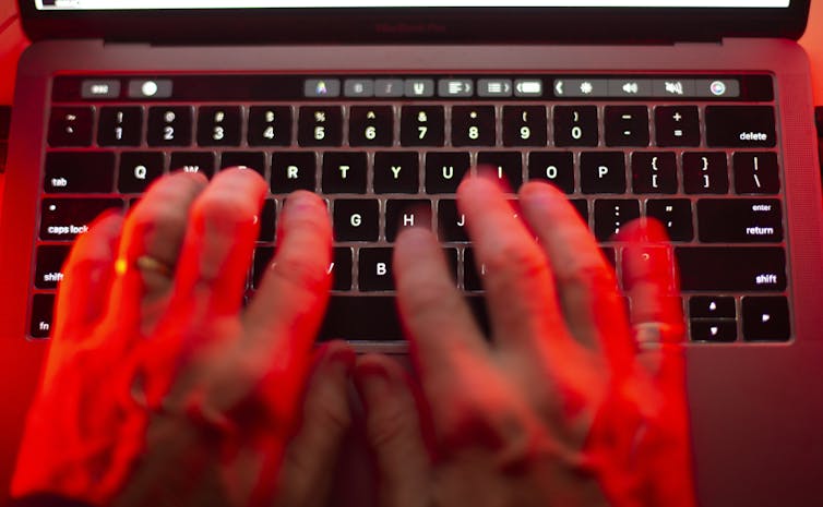 Manos en el teclado debajo de la luz roja.