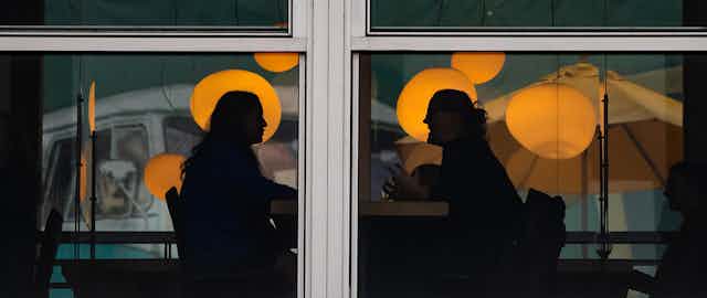 Two people are silhouetted while having a conversation.