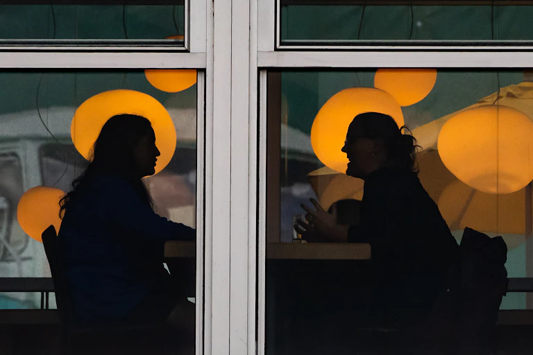Two people are silhouetted while having a conversation.