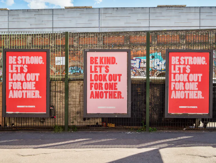 Red and pink posters reading 'be kind, be strong, let's look out for one another'