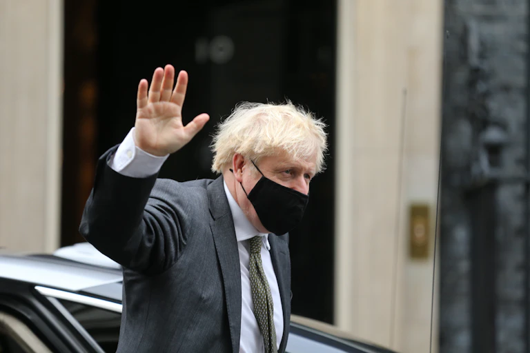 Boris Johnson wearing a face mask and waving as he walks outside Number 10