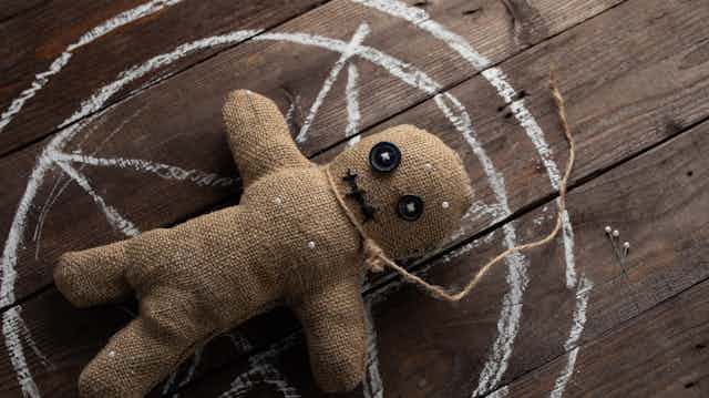 Muñeco vudú sobre una tabla de madera.