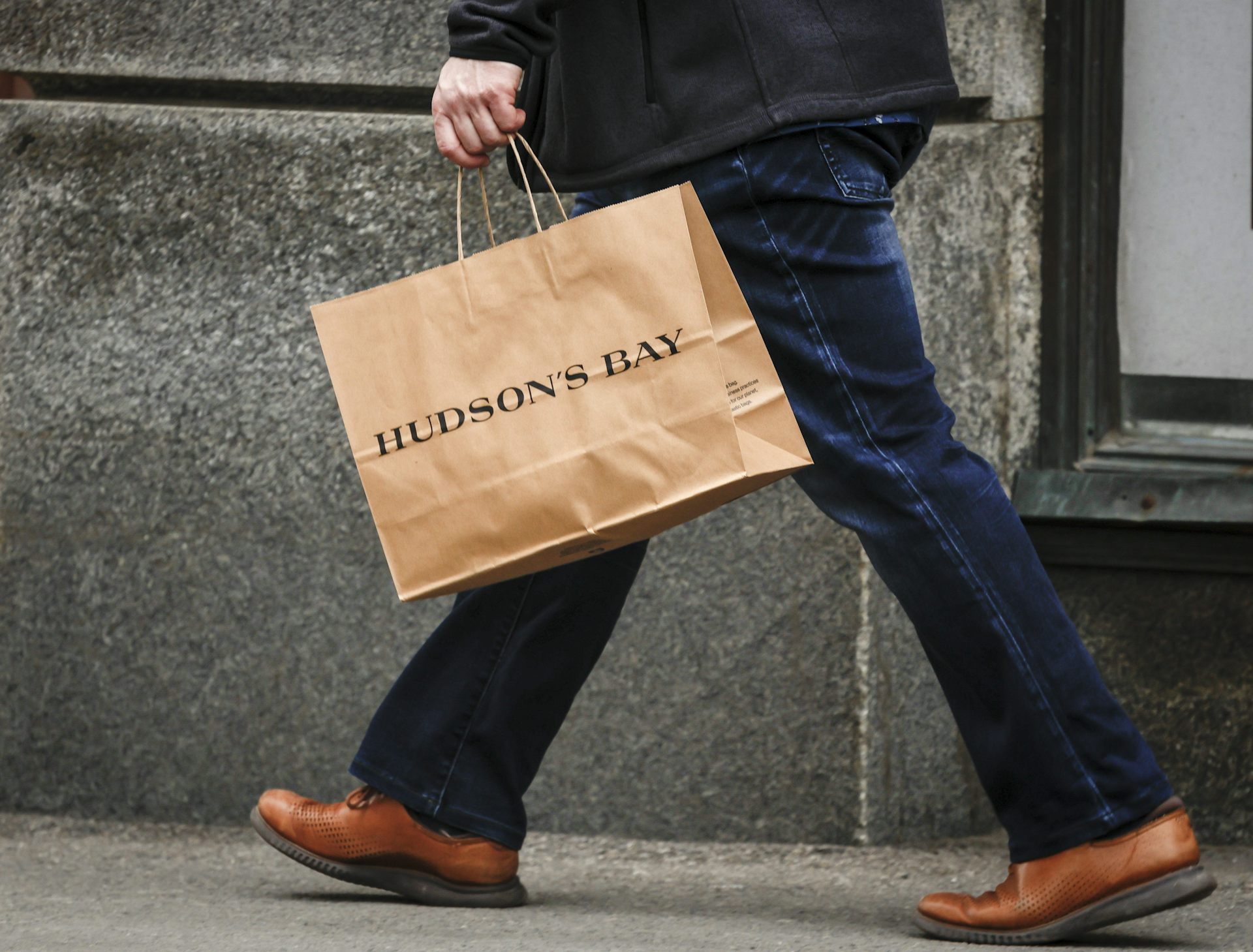 Closeup of a person's hand holding a paper shopping bag that says Hudson's Bay