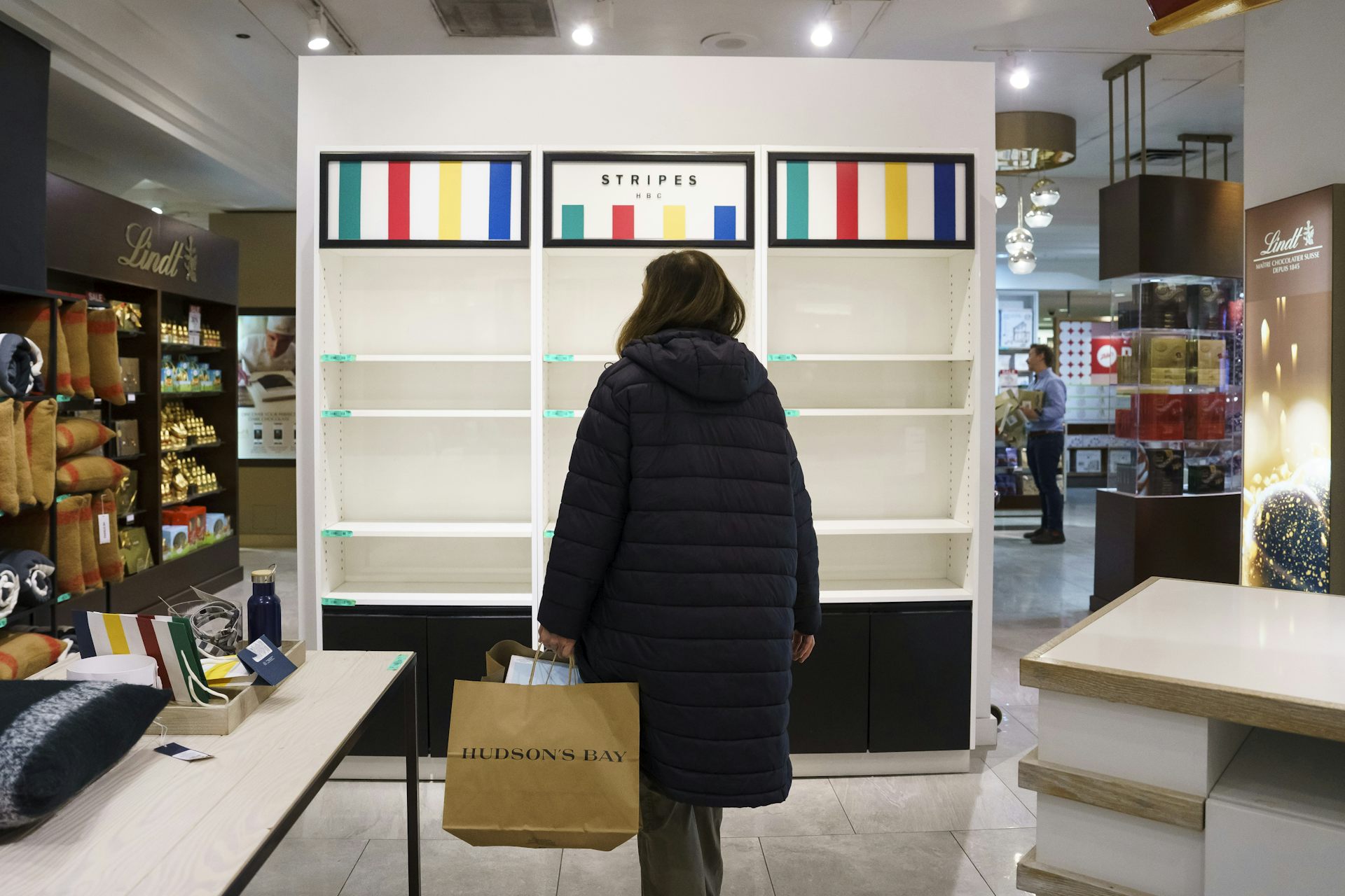 A woman, seen from behind, stands in front of empty shelves in a department store