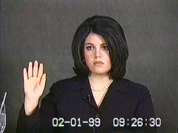 Monica Lewinsky holds her hand up to swear on the bible.