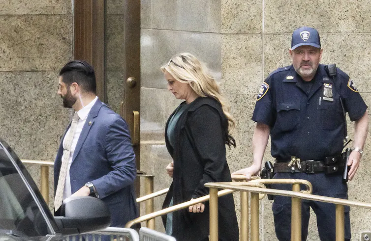 A woman in a dark suit outside a courtroom.