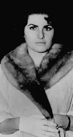 A dark-haired woman in a fur-trimemd coat.