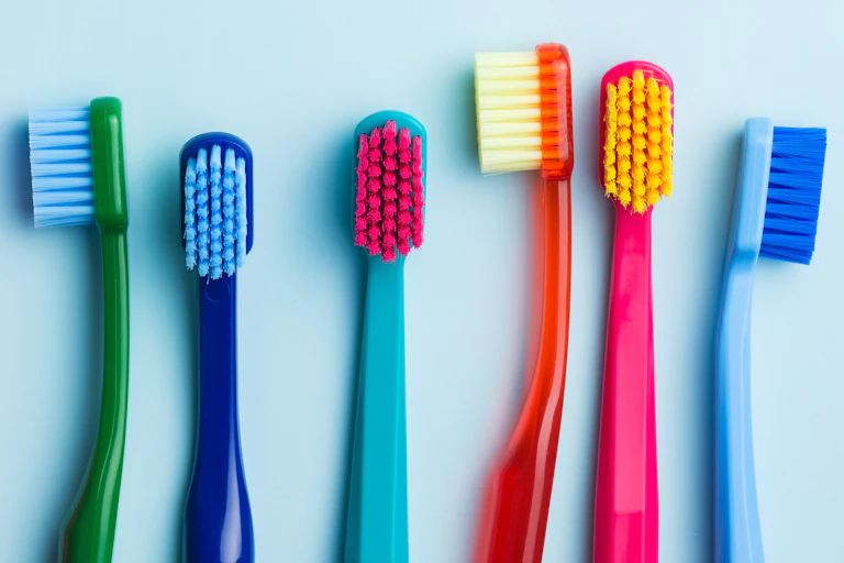 Row of colourful toothbrush heads against a blue background.