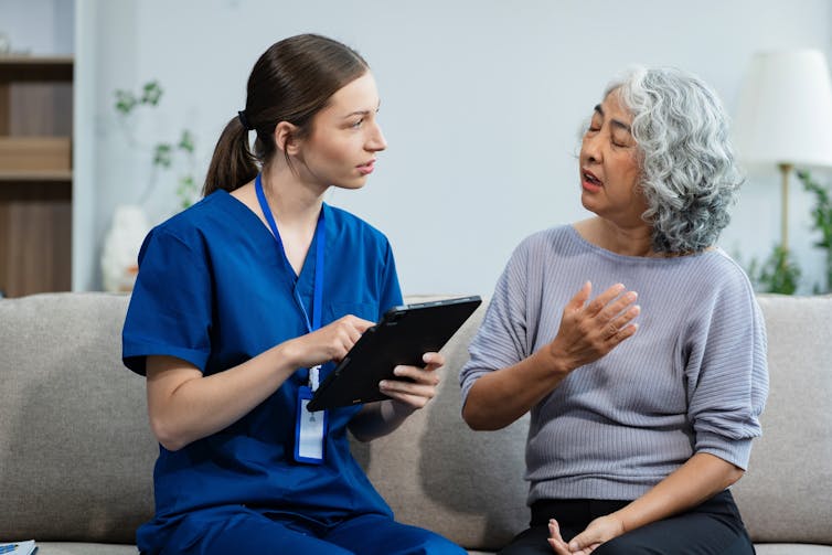 A young nurse talks to a senior woman.