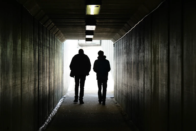 Two figures walking through tunnel