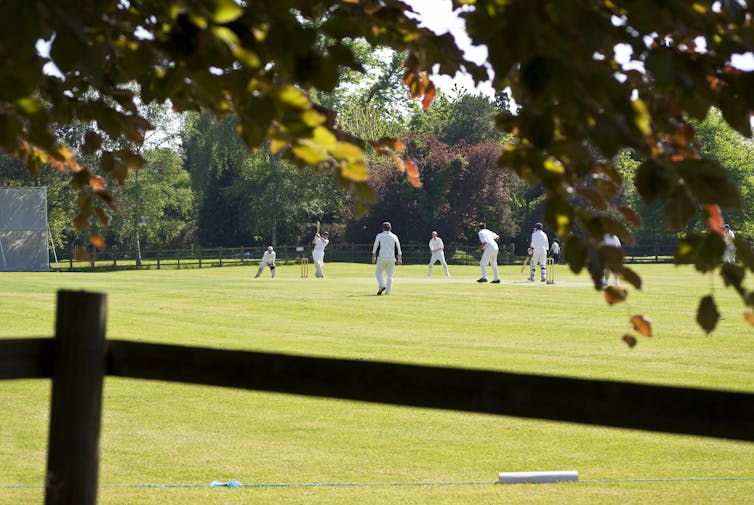 Village green cricket match in progress.
