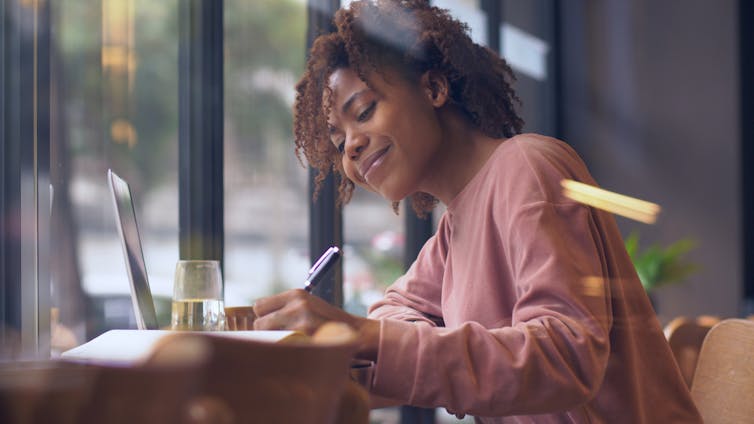 A woman at a table writing.
