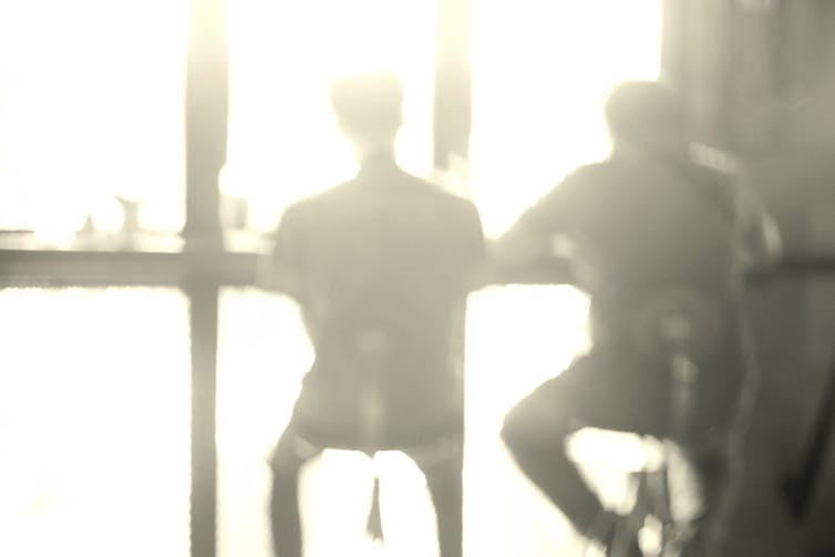 Blurred image of two figures sat at bar in window