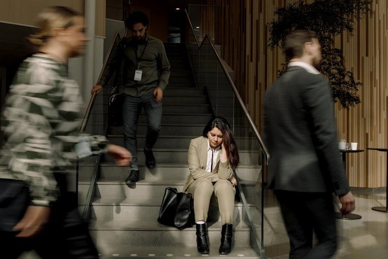 Frustrated businesswoman sitting on staircase at convention center.