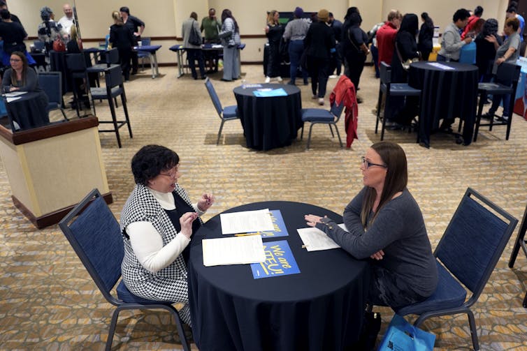 Two women hold a meeting in a big conference room.