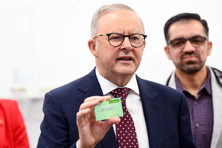 The PM holds a Medicare card at a press conference