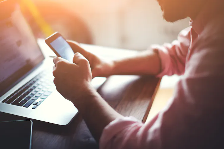 Close-up of worker using their phone and laptop.