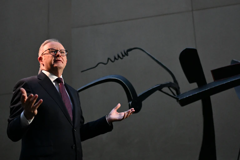 Man in black suit gesturing with hands