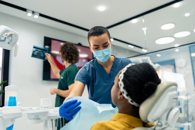 A dental assistant prepares a dental patient for a procedure.