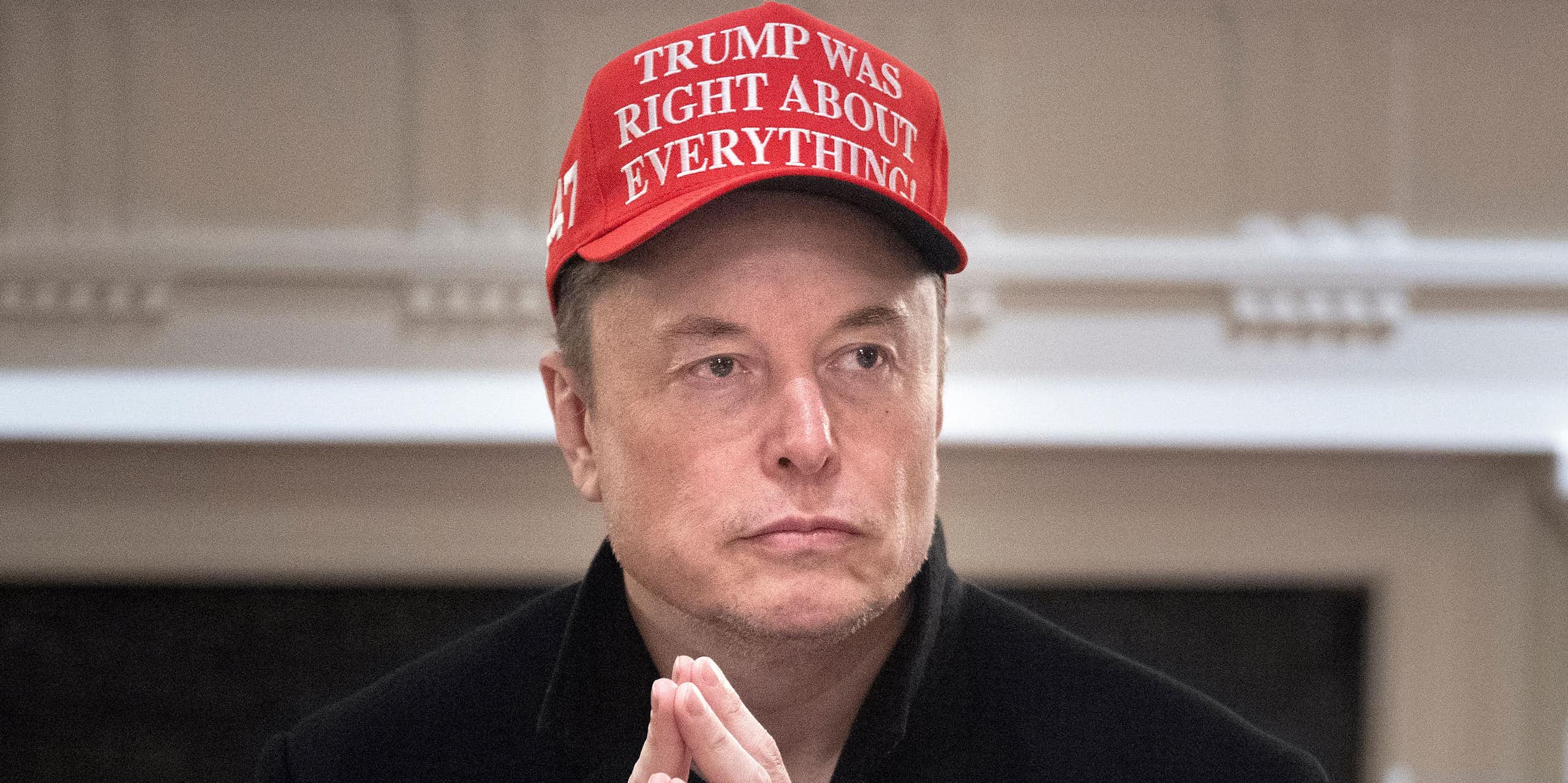 Portrait d'Elon Musk les mains jointes avec une casquette rouge sur laquelle est écrit 'Trump avait raison sur tout' (en anglais évidemment)