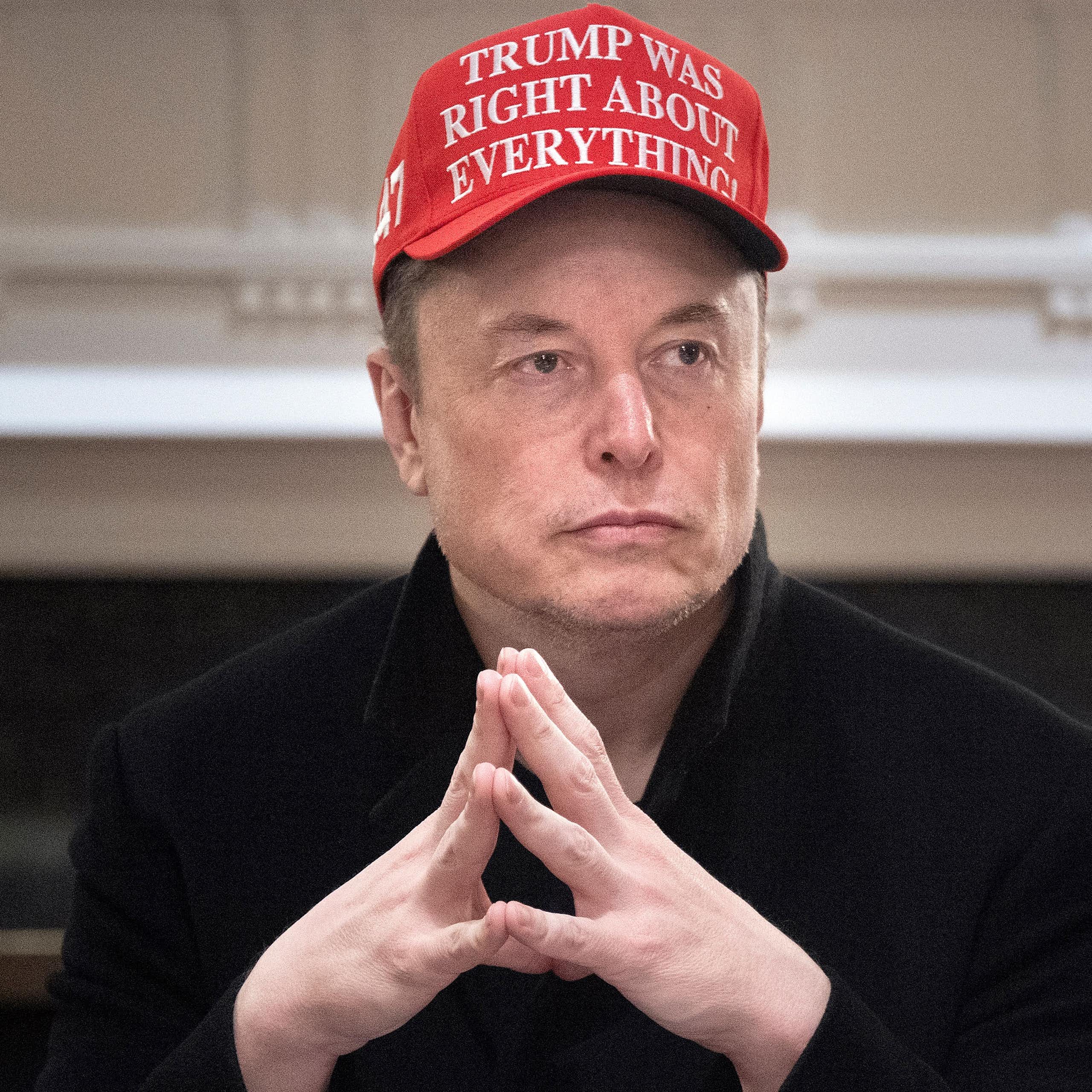 Portrait d'Elon Musk les mains jointes avec une casquette rouge sur laquelle est écrit 'Trump avait raison sur tout' (en anglais évidemment)