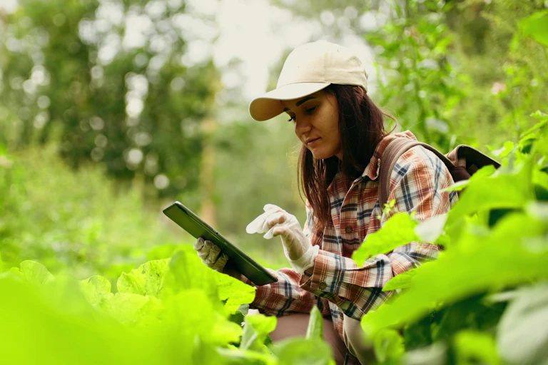 Woman studying plants outside with tablet