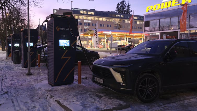 Cars plugged into public chargers in a wintry, urban setting.