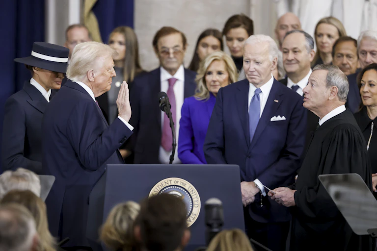 Donald Trump holds up his right hand as he takes the presidential oath of office, January 20, 2025.