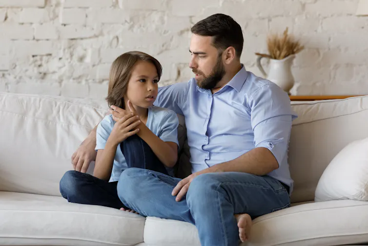 Un père assis sur un divan avec son enfant