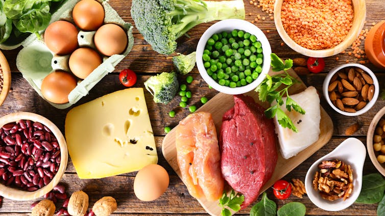 A selection of different protein sources arranged on a tabletop, such as peas, red meat, chicken and beans.