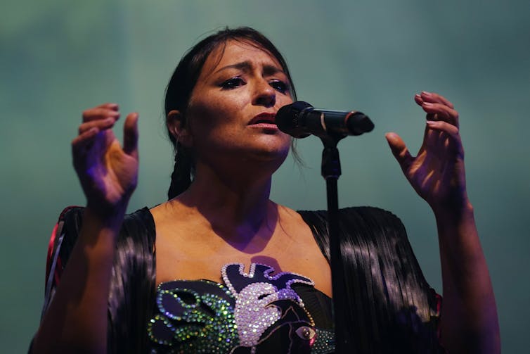 Mujer con las manos levantadas, canta