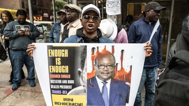 A man holds a placard with an image on it.