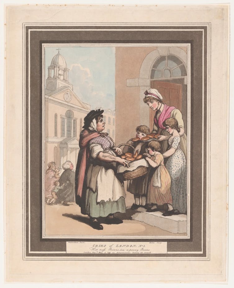 Three children and their mother reach for buns in a basket.
