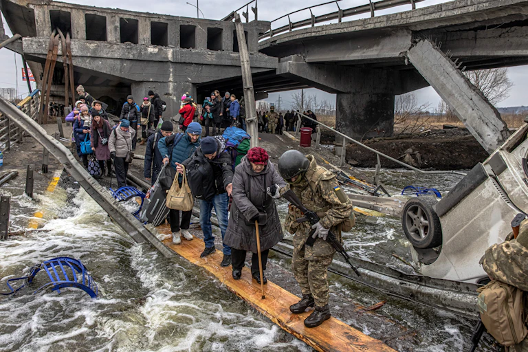 People crossing a river on planks as bridge is destroyed