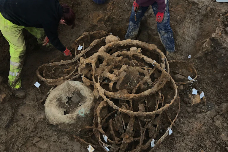 Bent iron tyres and a cauldron at the excavation site.
